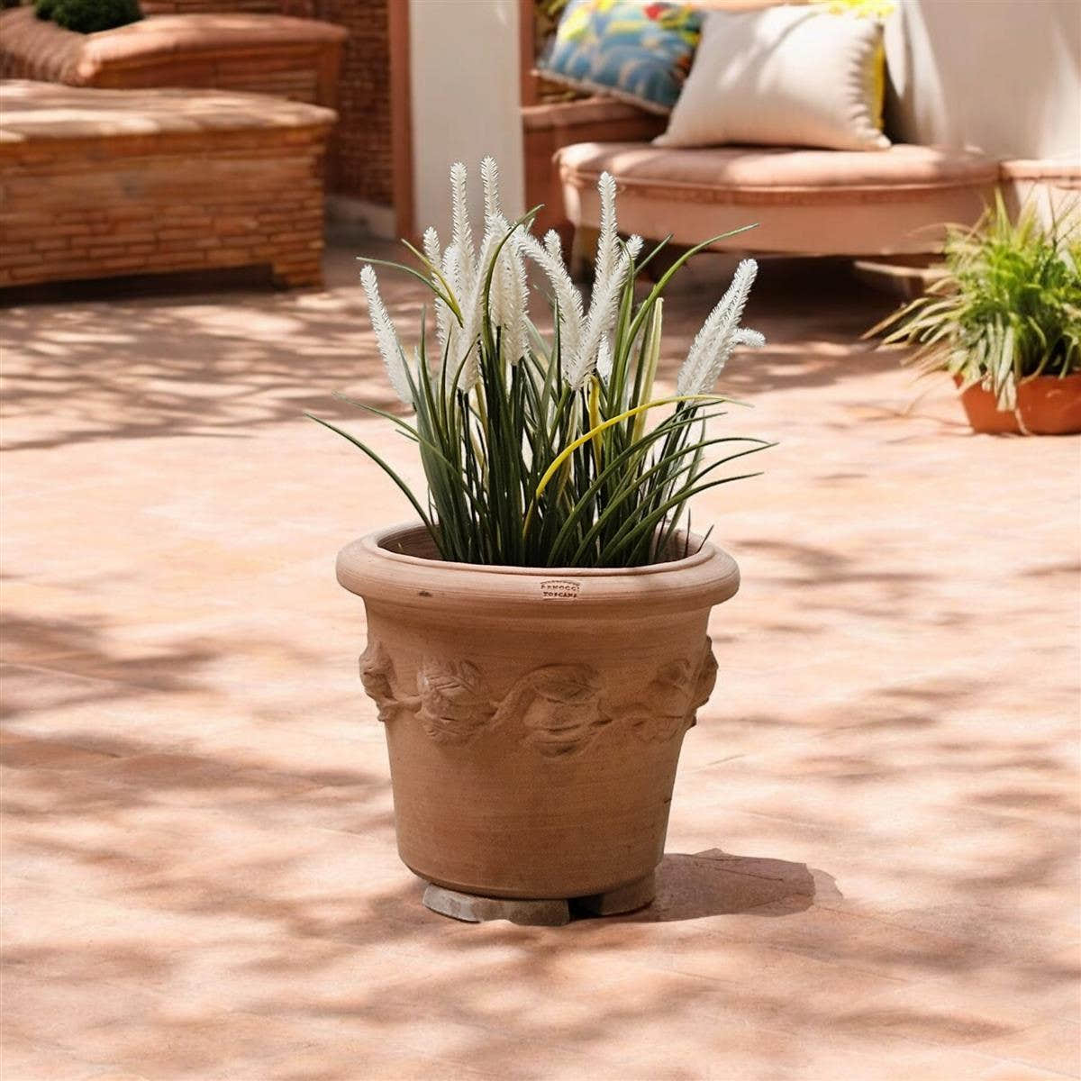 Bepflanzter Terrakotta-Topf auf Pflanzfüßen auf einer Terrasse